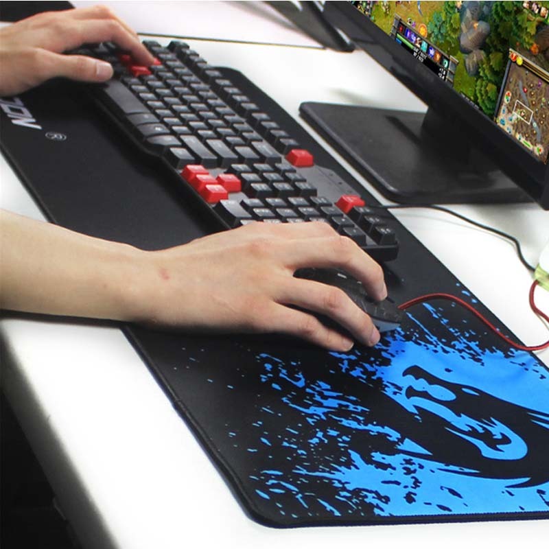 Person playing a game on a computer with a large mouse pad and keyboard.