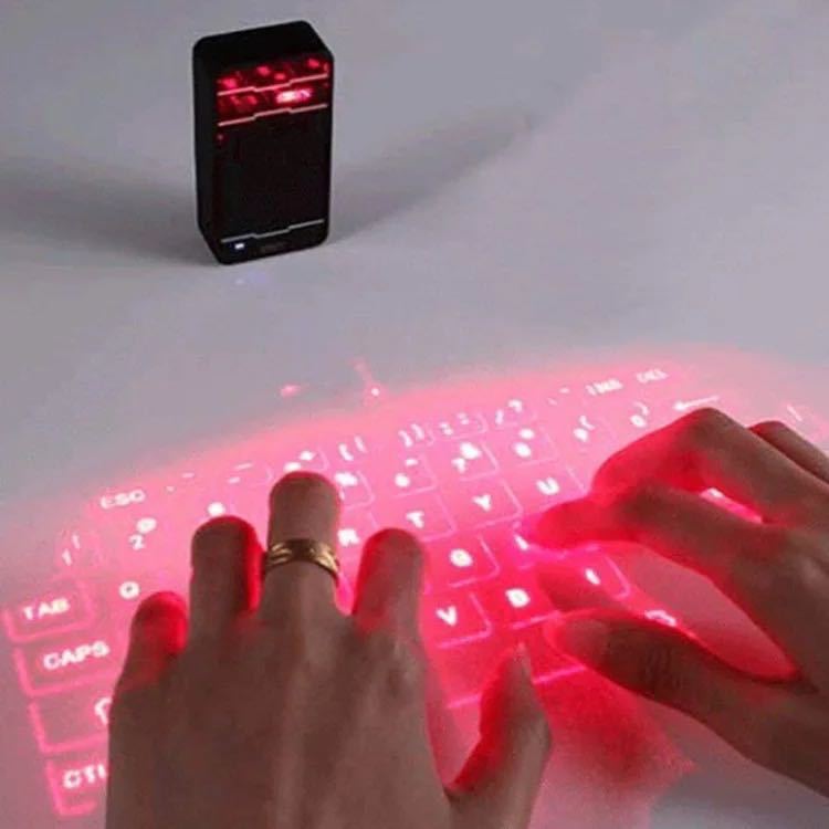 Hands interacting with a virtual red keyboard projected onto a surface, with a small black device emitting red light.