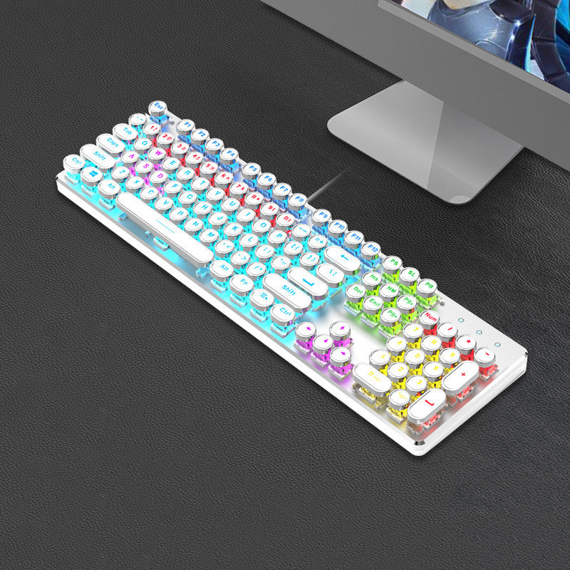 Colorful mechanical keyboard on a dark surface with a computer monitor in the background