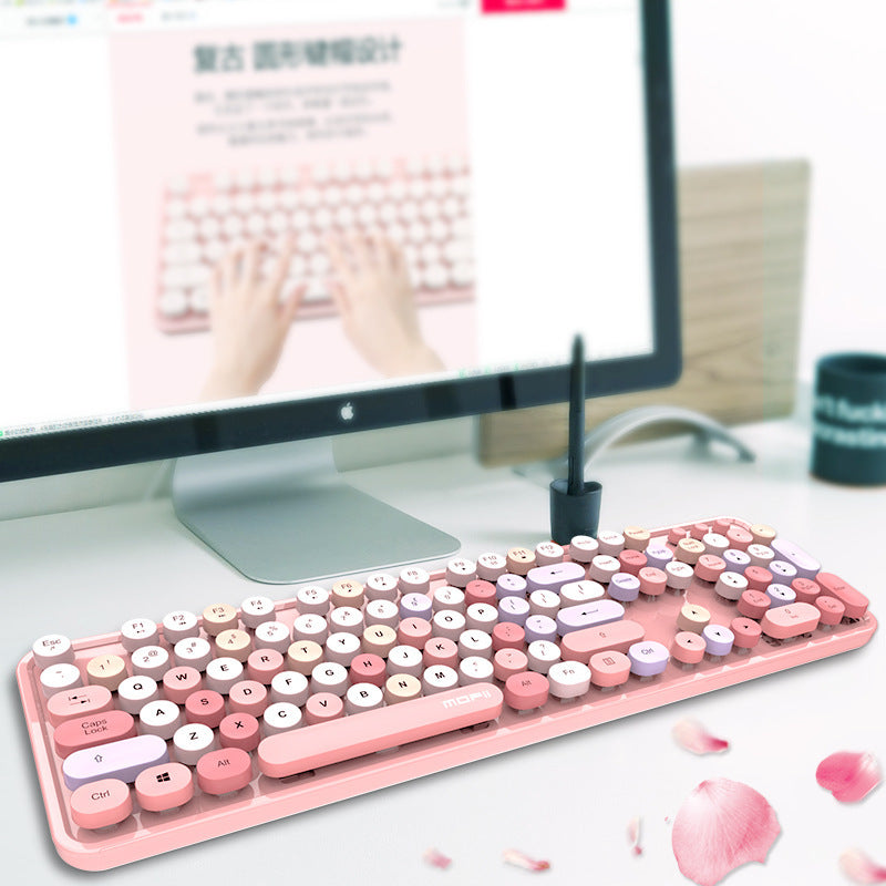 Pink and white keyboard on a desk with a computer monitor in the background