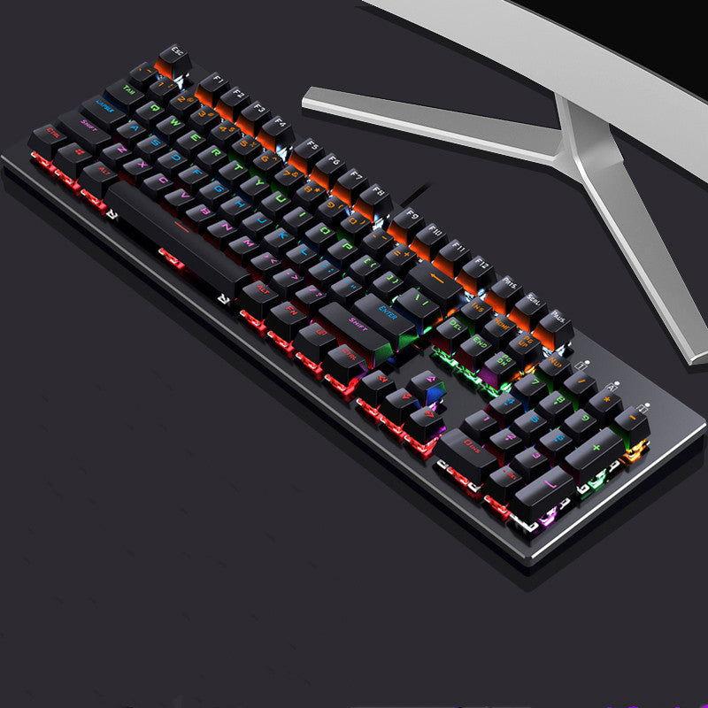Gaming keyboard with RGB lighting on a dark surface with a monitor in the background