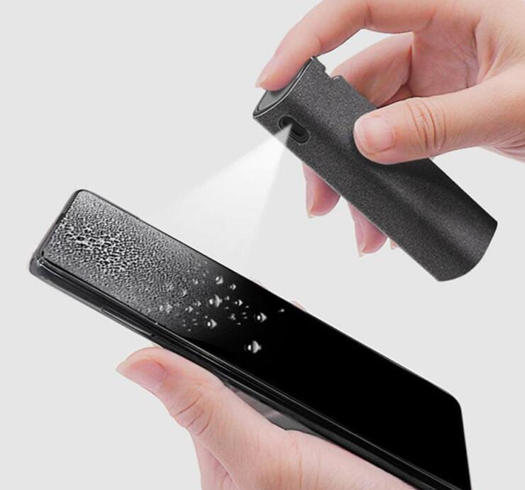 Person using a black handheld device to clean a smartphone screen on a white background