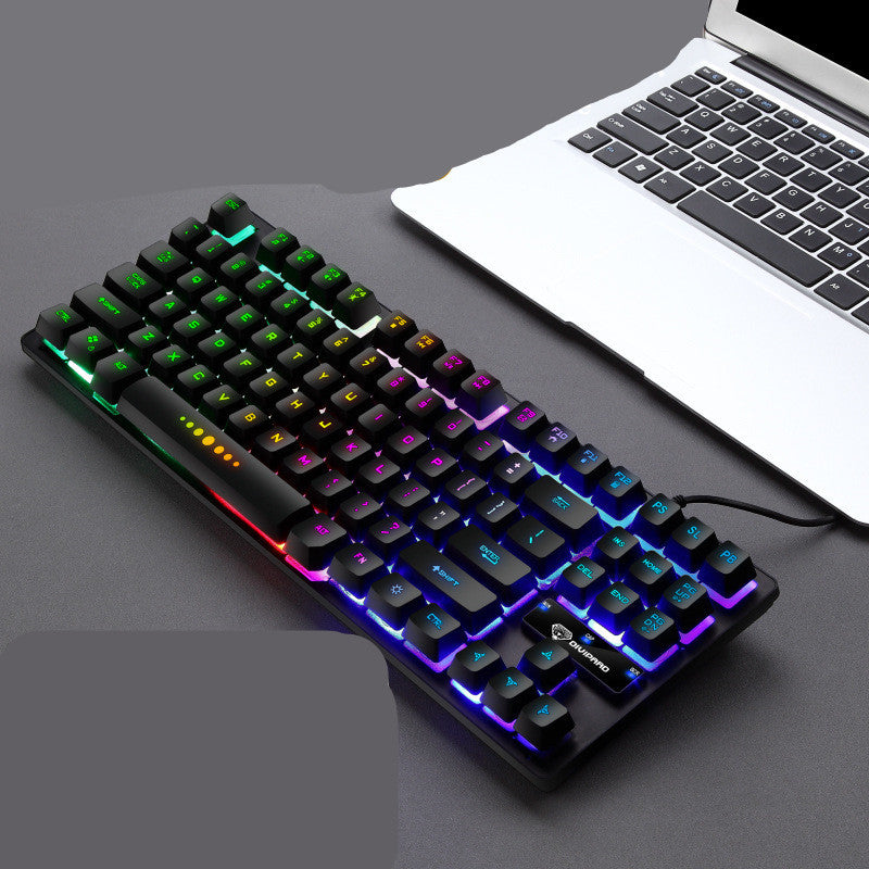 Mechanical keyboard with RGB lighting next to a laptop on a dark surface