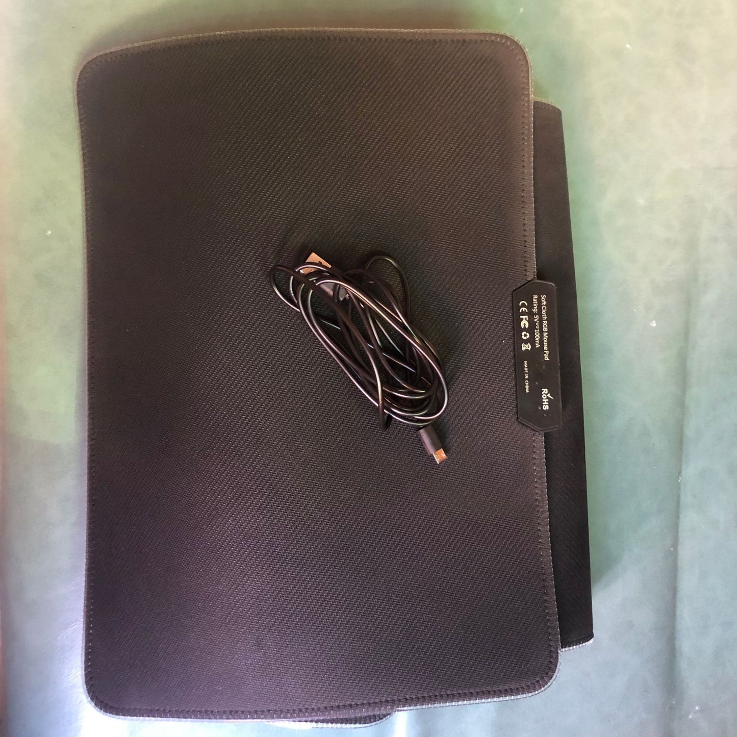 Black electronic device with a cable on a light green surface