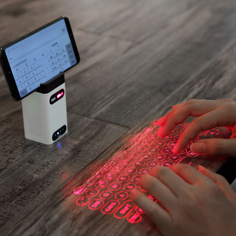 Person using a red laser keyboard projected onto a wooden surface with a smartphone displaying text.