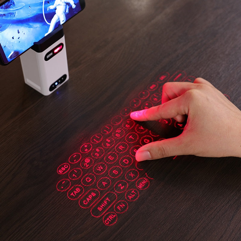 Hand interacting with a red laser projected keyboard on a dark surface, with a smartphone displaying a game in the background.