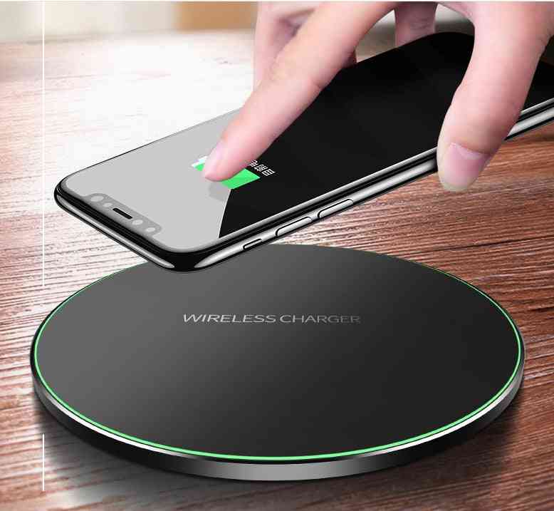 Hand placing a smartphone on a wireless charger with a wooden surface background