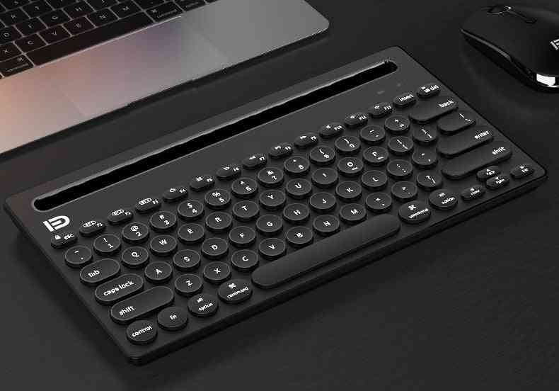 Black keyboard on a desk with a laptop and mouse in the background