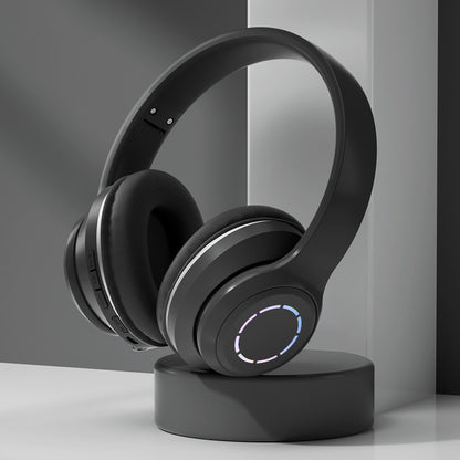 Black over-ear headphones with a glowing circle on a stand against a gray background