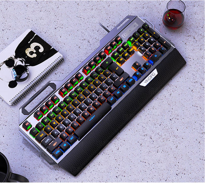 Mechanical keyboard with RGB lighting on a gray surface with a glass of red wine and notebook.