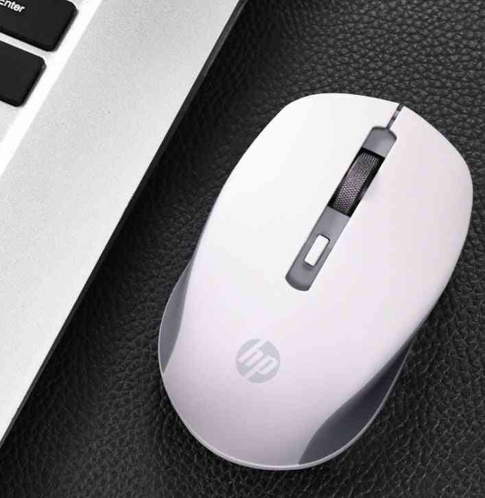 White HP mouse on a black surface next to a laptop
