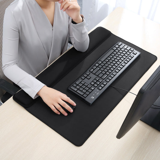 Person using a large black desk mat with a keyboard on a desk.