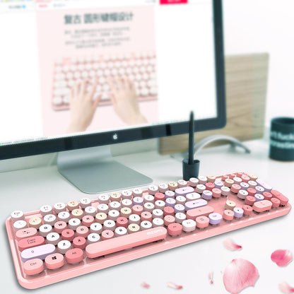 Pink and white keyboard on a desk with a computer monitor in the background