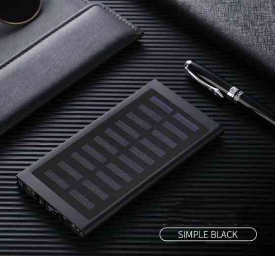 Black solar power bank on a textured surface with a pen and wallet.
