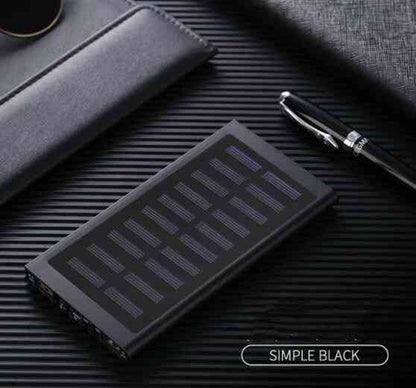 Black solar power bank on a textured surface with a pen and wallet.