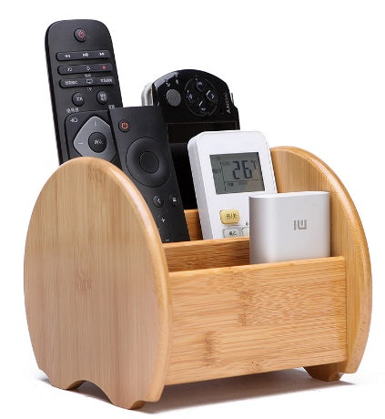 Wooden remote control holder with electronic devices including a camera, remote controls, and a digital thermometer.