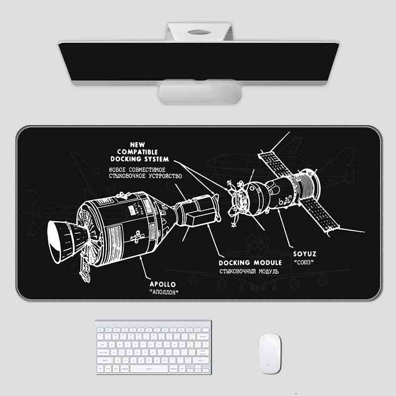 Space-themed mouse pad with spacecraft design on a desk setup.
