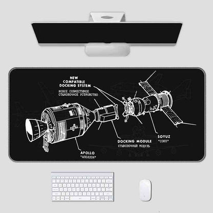 Space-themed mouse pad with spacecraft design on a desk setup.