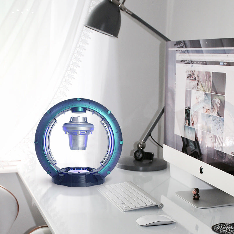 Desk setup with a futuristic circular lamp and computer monitor.