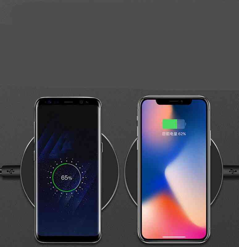 Two smartphones on wireless charging pads with battery percentage displayed.
