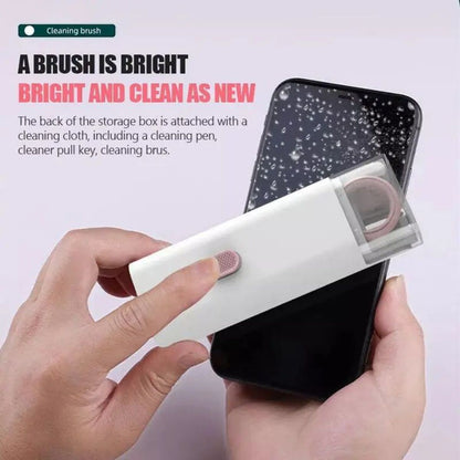 Hand holding a smartphone with cleaning brush and cloth attached to storage box on a light pink background.