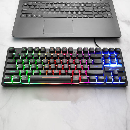 Mechanical keyboard with RGB lighting on a white surface, next to a laptop.
