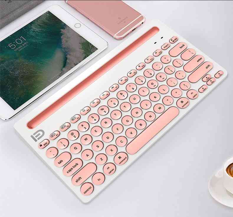 Rose gold keyboard on a white surface with a smartphone and tablet in the background.
