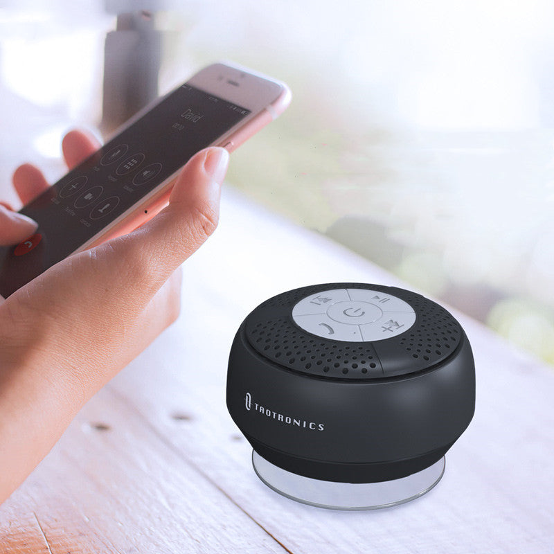 Black Bluetooth speaker with remote control on a light surface
