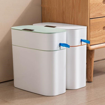 Two white trash bins with green lids on a wooden floor.