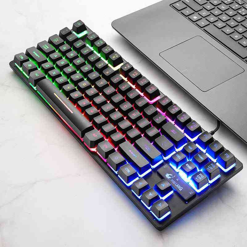 Mechanical keyboard with RGB lighting next to a laptop on a light surface