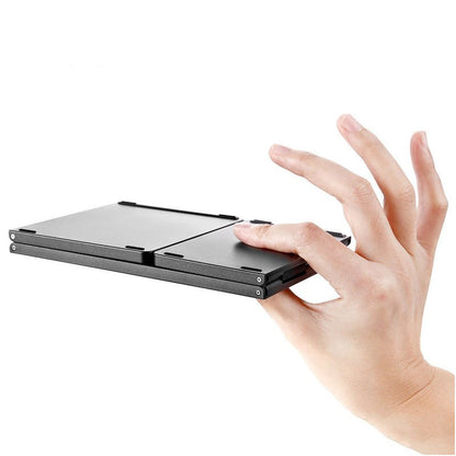 A black foldable keyboard device being held by a person's hand against a plain white background.