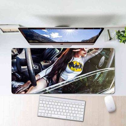 Desk setup with a monitor, keyboard, and mouse on a desk mat featuring a person in a car.