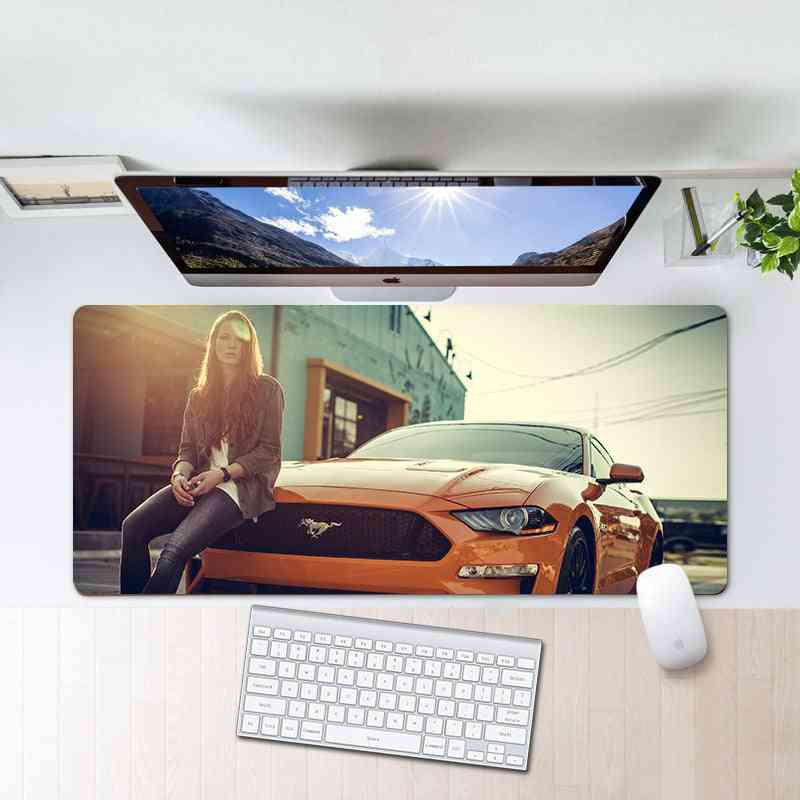 Desk setup with a large mouse pad featuring a woman and car design, keyboard, and mouse.