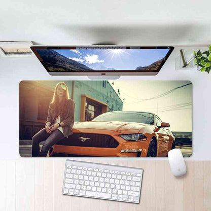 Desk setup with a large mouse pad featuring a woman and car design, keyboard, and mouse.