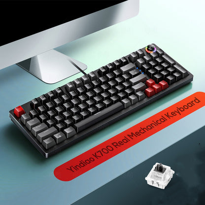 Mechanical keyboard with red escape key on a desk next to a computer monitor, with a label indicating brand and model.