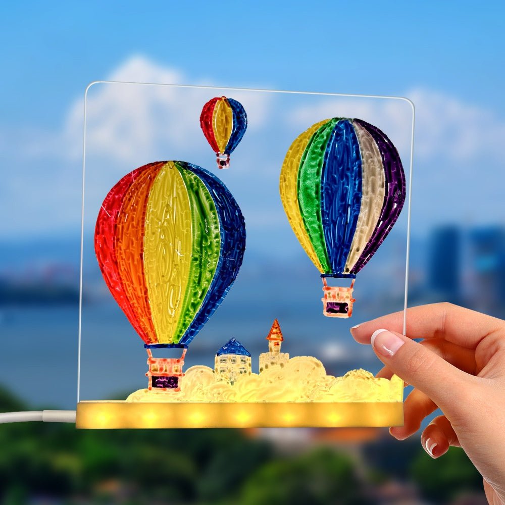 Colorful hot air balloons on a transparent panel held by a hand with a blurred cityscape background