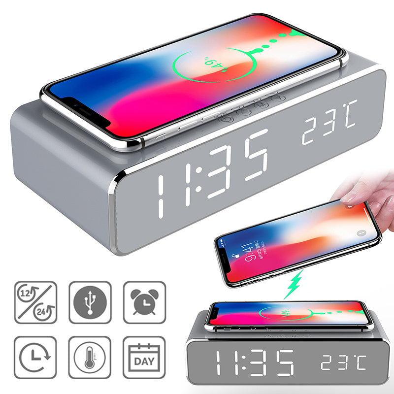Gray digital clock with wireless charging pad and smartphone on top, displaying time and temperature.
