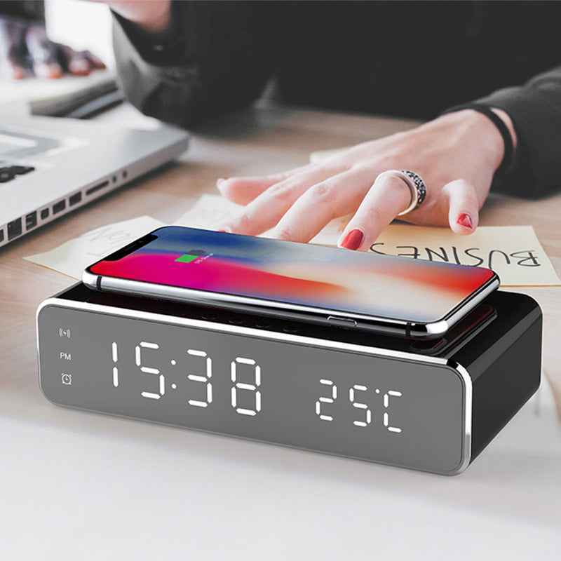 Smart clock with wireless charging pad on a desk with a phone on top