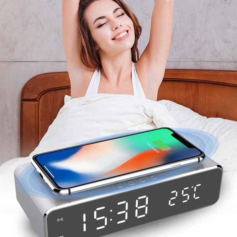 Smart phone charging pad with digital clock and temperature display on a bed.