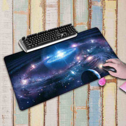 Large galaxy-themed mouse pad with a keyboard on a wooden surface.