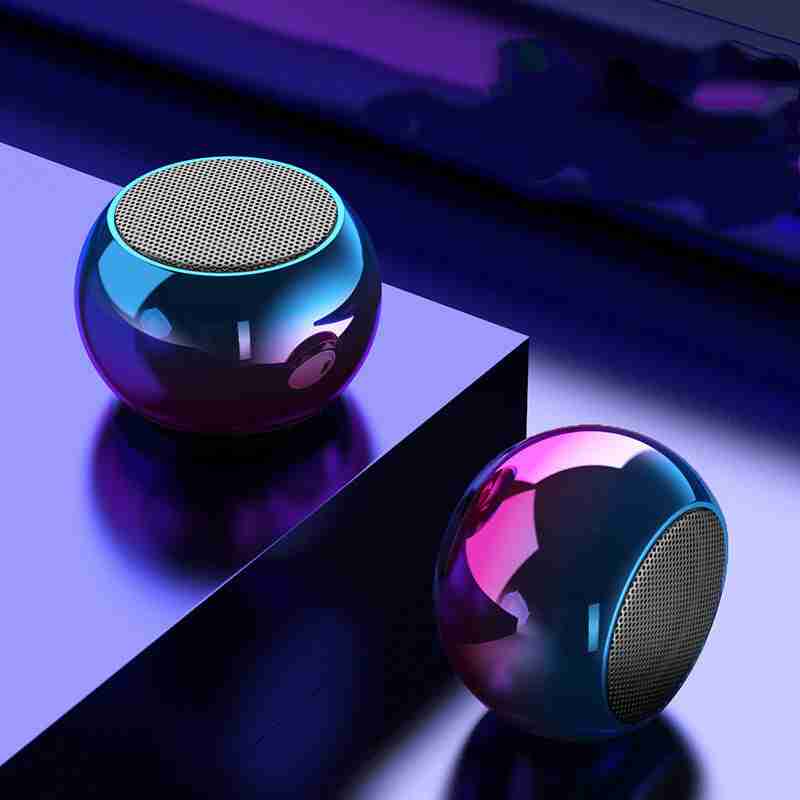 Two metallic spherical speakers on a reflective surface with a dark background