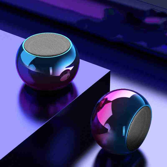 Two metallic spherical speakers on a reflective surface with a dark background