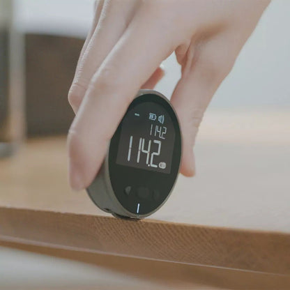 Digital thermometer held by a hand with a blurred background