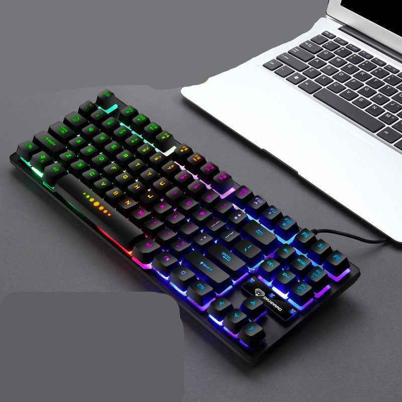 Mechanical keyboard with RGB lighting next to a laptop on a gray surface