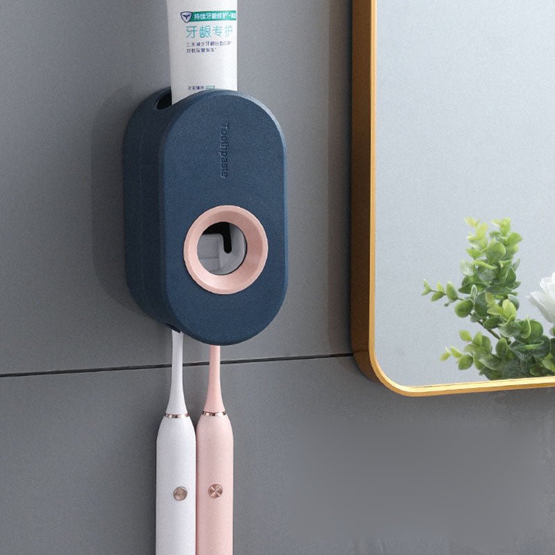 Wall-mounted toothbrush holder with two electric toothbrushes and a tube of toothpaste on a gray wall.