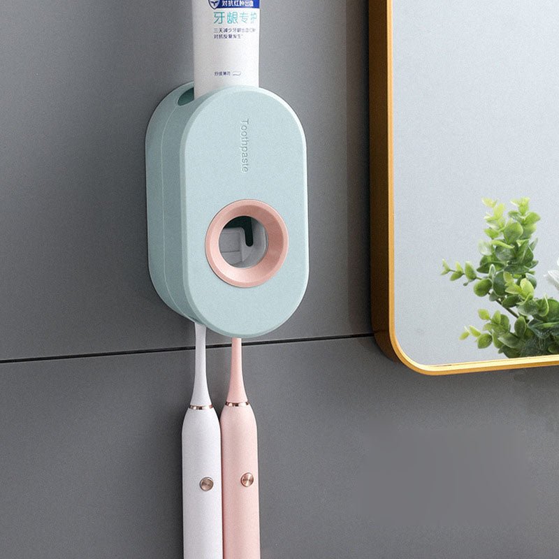 Wall-mounted toothbrush holder with two toothbrushes and a tube of toothpaste on a gray wall.