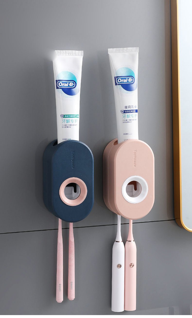 Two toothbrushes and toothpaste tubes mounted on a gray wall.