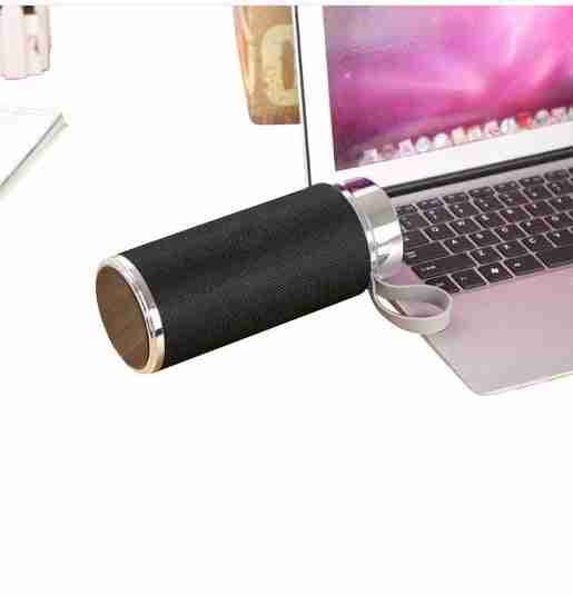 Black cylindrical speaker with silver accents on a laptop