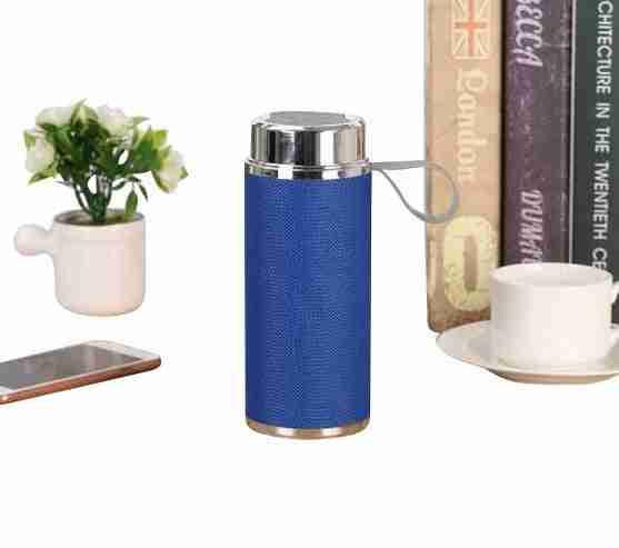 Blue thermos with silver top on a white surface next to a plant, phone, and books.