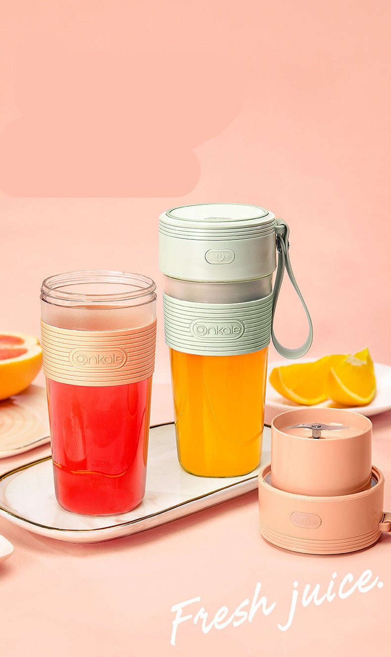 Juice blender with a glass of juice on a pink background